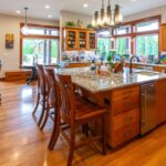 Full view of the spacious kitchen from the dining area showing ample cabinetry and modern lighting, listed by Andi Dyer