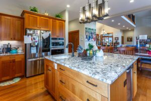 Detailed kitchen view highlighting stainless steel appliances, cherry wood cabinets, and granite countertops, listed by Andi Dyer