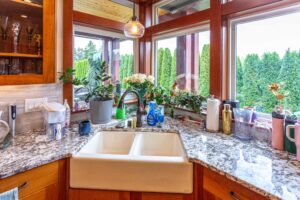 Kitchen counter view showcasing the farmhouse sink, granite countertops, and decorative window garden, listed by Andi Dyer