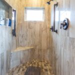 A fully tiled shower area featuring a built-in seat and a single frosted glass window. Listed by Andi Dyer.