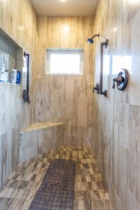 A fully tiled shower area featuring a built-in seat and a single frosted glass window. Listed by Andi Dyer.