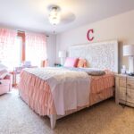 A room enhanced with pink accents, including curtains and decorative items, complete with personalized touches. Listed by Andi Dyer.