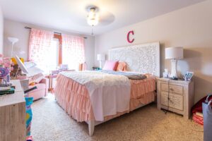 A room enhanced with pink accents, including curtains and decorative items, complete with personalized touches. Listed by Andi Dyer.