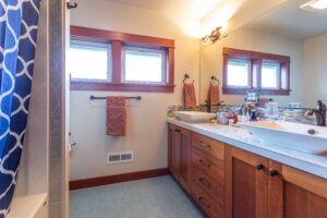 A functional bathroom space with dual sinks, large mirrors, and a full bathtub obscured by a stylish curtain. Listed by Andi Dyer.