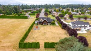 Captures an overhead view of residential homes set within a lush landscape. Listed by Andi Dyer.